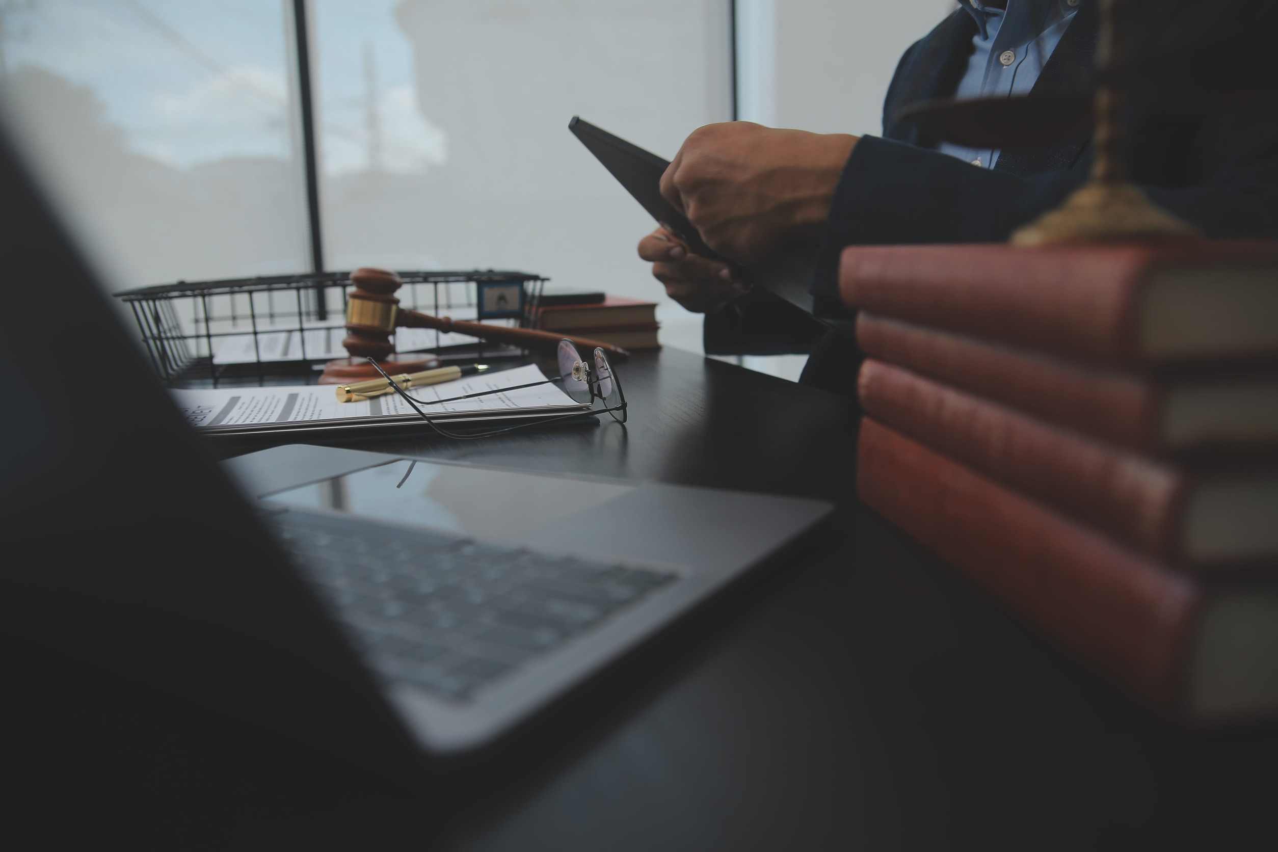 Man at desk with laptop, glasses, and various legal paraphernalia