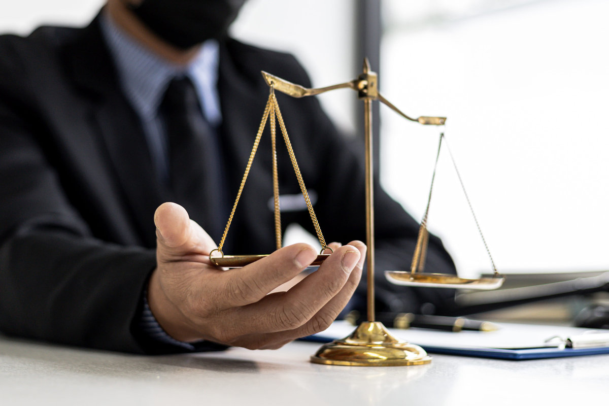 Lawyer cupping his hand beneath one of the two scales of justice